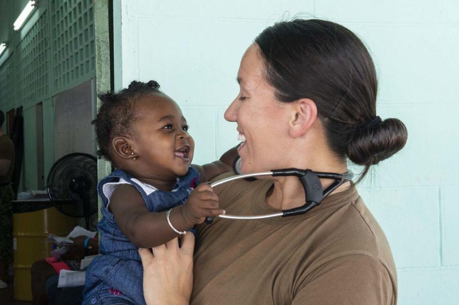 A Capitão de Corveta da Marinha dos EUA Jennifer Eng-Kulawy, uma pediatra lotada no navio-hospital USNS Comfort, carrega uma menina em uma unidade médica provisória em La Brea, Trinidad e Tobago, no dia 7 de setembro de 2019. (Foto: Terceiro-Sargento da Marinha dos EUA Bobby J. Siens)