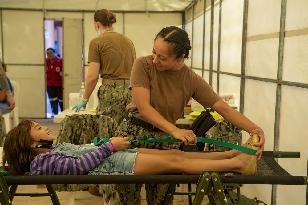 A enfermeira Cabo Marybeth Vargas-Romero, destacada no navio hospital USNS Comfort (T-AH 20), ajuda uma paciente a esticar suas pernas em um local de atenção médica em Honduras, em 5 de novembro de 2022. (Foto: Marinheiro Deven Fernandez, da Marinha dos EUA)