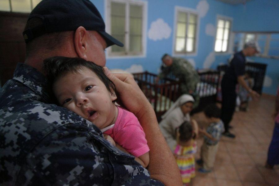 O Capitão-de-Corveta e capelão da Marinha dos EUA Michael Vitcavich segura uma criança guatemalteca no abrigo infantil La Asunción, em Puerto Barrios, Guatemala, na missão humanitária Promessa Contínua 2018, no dia 13 de abril. (Foto: Segundo-Sargento do Exército dos EUA Daniel Luksan)