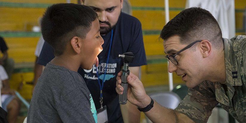 U.S. Air Force Captain Nicholas Singh-Miller, assigned to the Naval Medical Center in Portsmouth, Massachusetts, examines a child's mouth during a physical at the Franklin D. Roosevelt School in Puerto Cortés, Honduras, during SOUTHCOM's 2018 Continuing Promise mission. (Photo: U.S. Navy Specialist Second Class Brianna K. Green) 