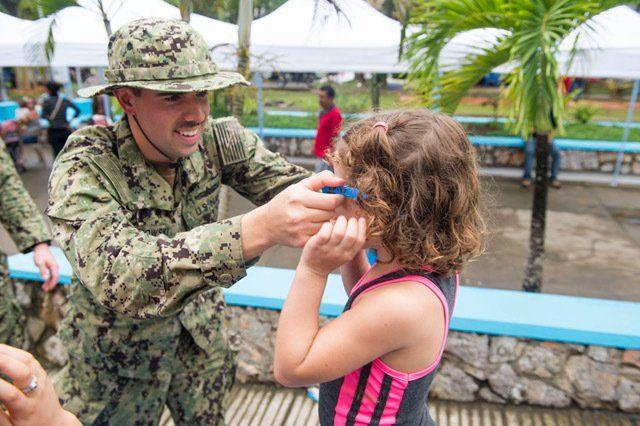 O 1º Ten da Marinha dos EUA Jack Dembowski, que serve no Esquadrão de Destróieres 40, coloca óculos de sol em uma paciente na instalação médica da CP-17 em Puerto Barrios, na Guatemala. (Foto: Segundo Sargento Especialista em Comunicação Social Shamira Purifoy/Marinha dos EUA)