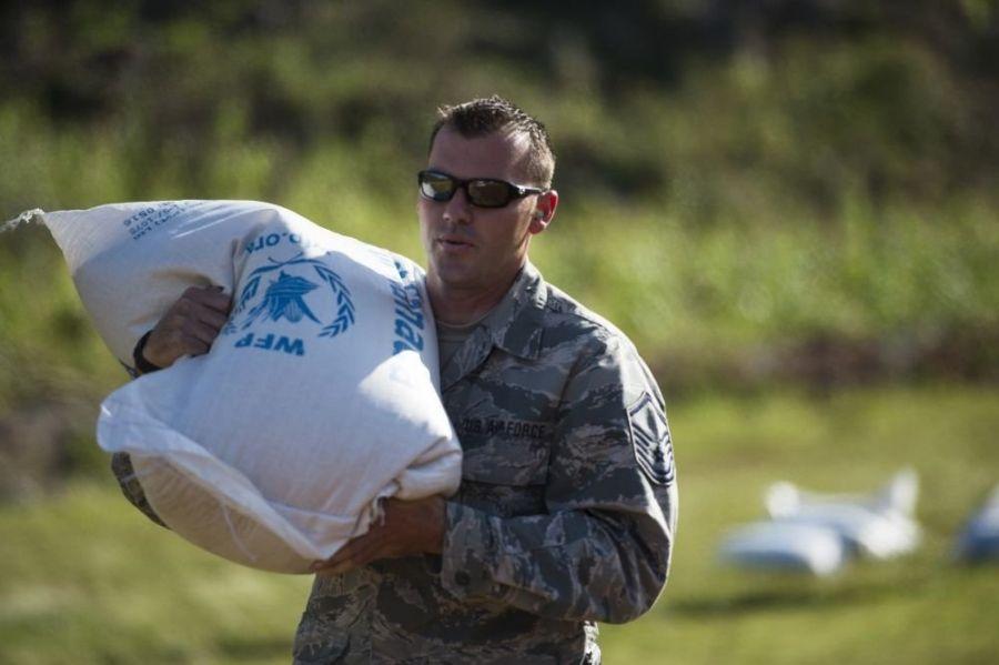 O Sargento Gabriel Peterson da Força Aérea dos EUA e parte da Força-Tarefa Conjunta Matthew, juntamente com o 290º Regimento de Suporte de Comunicações Conjuntas, distribui suprimentos aos cidadãos de Beaumont, Haiti, dia 13 de outubro de 2016. (Foto: Sgt Russ Scalf /Força Aérea dos EUA) 