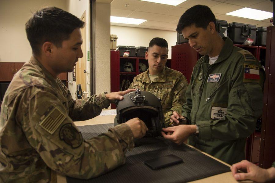 U.S. Air Force Senior Airman Matthew Morales, 563rd Operations Support Squadron, aircrew flight equipment technician, issues a helicopter helmet to Chilean Air Force Major Javier Del Rio. (Photo: U.S. Air Force Technician Sergeant Angela Ruiz)