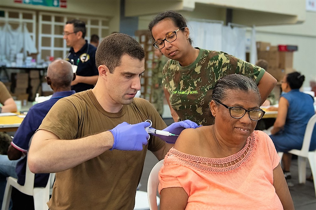 U.S. Navy Lieutenant Commander William Pullen (L) and Brazilian Army Captain Danielle Morel, both doctors attached to the USNS Comfort, administer a steroid shot to treat a woman’s torn rotator cuff at a temporary medical treatment site in Santo Domingo, Dominican Republic. (Photo: U.S. Navy Mass Communication Specialist Third Class Maria G. Llanos)