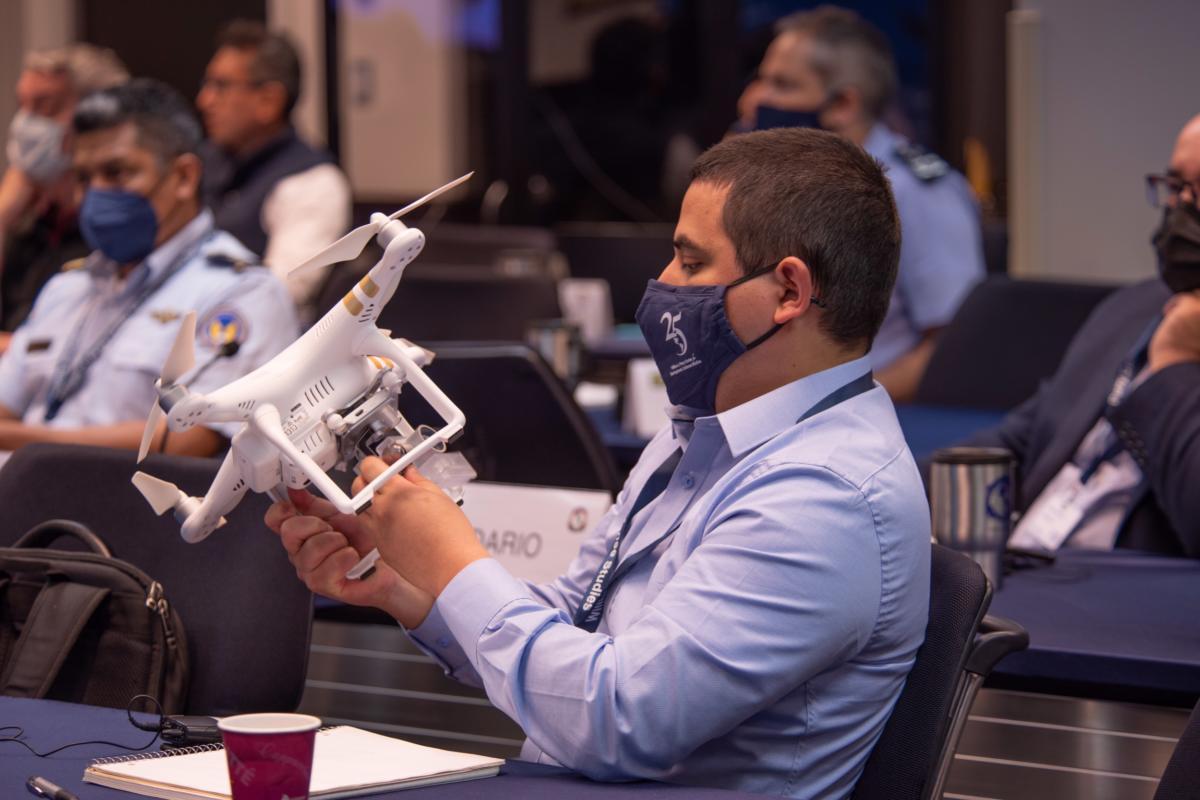 Um participante do curso Política de Segurança Cibernética nas Américas 2022 examina um drone, durante a sessão sobre Drones e Robótica, apresentado pelo Brigadeiro Frederick Roggero (R), da Força Aérea dos EUA. (Foto: Viviana Edwards/Centro William J. Perry)