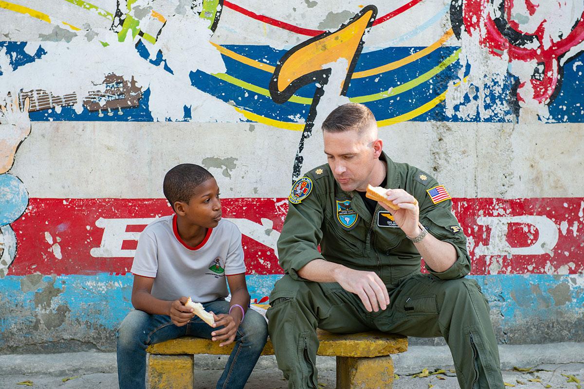 El Teniente de Navío Daniel Slot, oficial de enlace de la Embajada de los EE. UU. en la República Dominicana, come con un niño en la Fundación Ened, un orfanato en Boca Chica, República Dominicana, el 21 de febrero de 2023. Como parte del ejercicio Forward Tiger, los aviadores estadounidenses y sus homólogos de las naciones asociadas se unieron para inspirar a la juventud local. (Foto: Sargento Segundo de la Fuerza Aérea de los EE. UU. Jessica Smith)