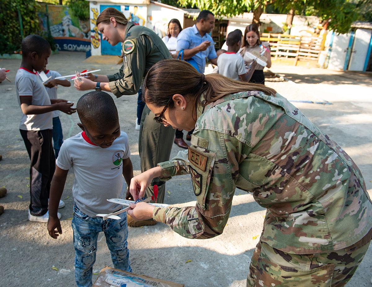 A Suboficial Keyla Watt, da Força Aérea dos EUA, gerente de Assuntos Internacionais de graduados da AFSOUTH, ajuda um menino a construir seu avião de brinquedo na Fundación Ened, em Boca Chica, República Dominicana, em 21 de fevereiro de 2023. (Foto: Segundo-Sargento Jessica Smith, da Força Aérea dos EUA)