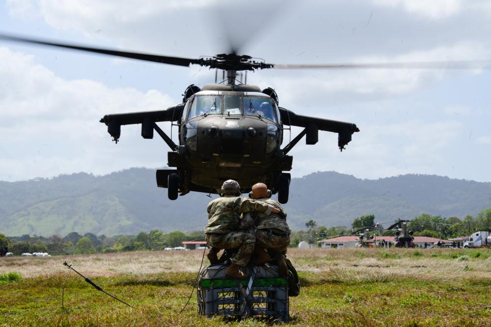 O Coronel do Exército dos EUA John Litchfield, comandante da JTF-Bravo, e outro membro da mesma força se preparam para prender com ganchos uma carga em um helicóptero UH-60 Black Hawk do Exército dos EUA, lotado no 1º Batalhão do 228º Regimento de Aviação da JTF-Bravo, durante o Exercício Mercúrio II, no Panamá, no dia 25 de janeiro de 2021. (Foto:  Terceiro-Sargento da Força Aérea dos EUA Elijaih Tiggs)
