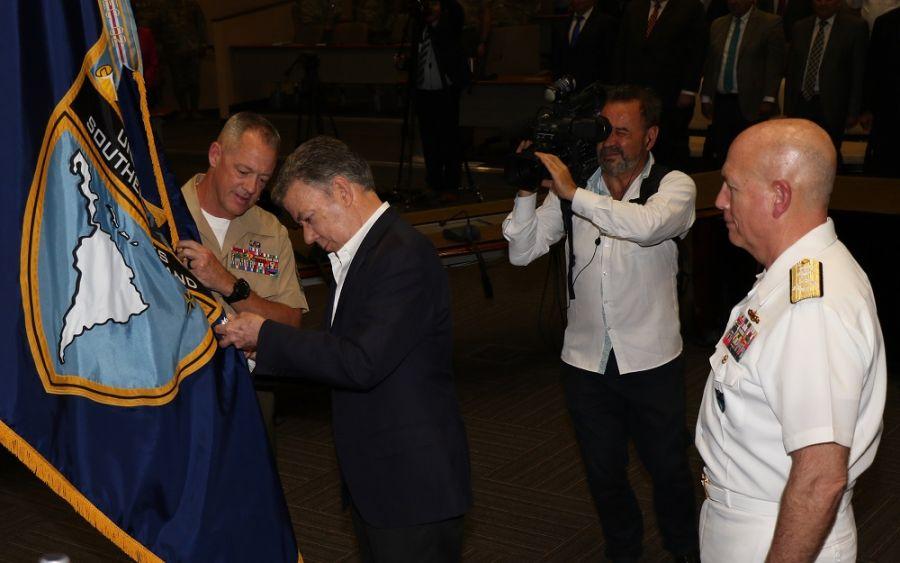 O presidente da Colômbia Juan Manuel Santos coloca a Medalha da Ordem de São Carlos na bandeira do SOUTHCOM, enquanto o Almirante-de-Esquadra da Marinha dos EUA Kurt W. Tidd, comandante do Comando Sul dos EUA, e o Suboficial do Corpo de Fuzileiros Navais dos EUA Bryan Zickefoose, adjunto de comando do SOUTHCOM, observam. (Foto: José Ruiz, Relações Públicas do SOUTHCOM)