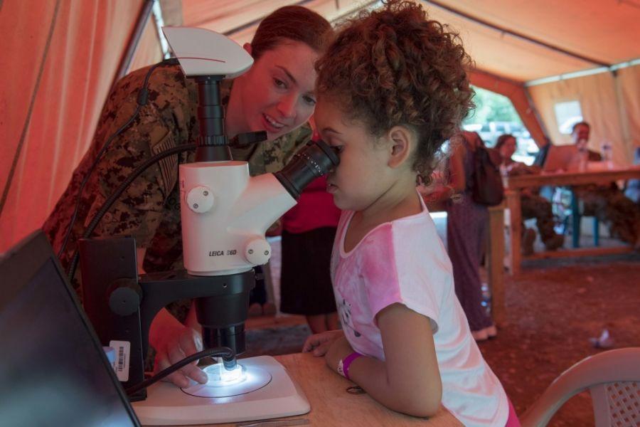 La Capitán de Corbeta de la Marina de los EE. UU. Amy Rogers, asignada a la Unidad Ambiental y de Medicina Preventiva de la Marina, muestra a una niña un mosquito capturado con una trampa para mosquitos fuera de la Escuela Franklin D. Roosevelt, en Puerto Cortés, Honduras, durante Promesa Continua 2018, el 17 de marzo de 2018. (Foto: Especialista Segunda Clase de la Marina de los EE. UU. Brianna K. Green) 