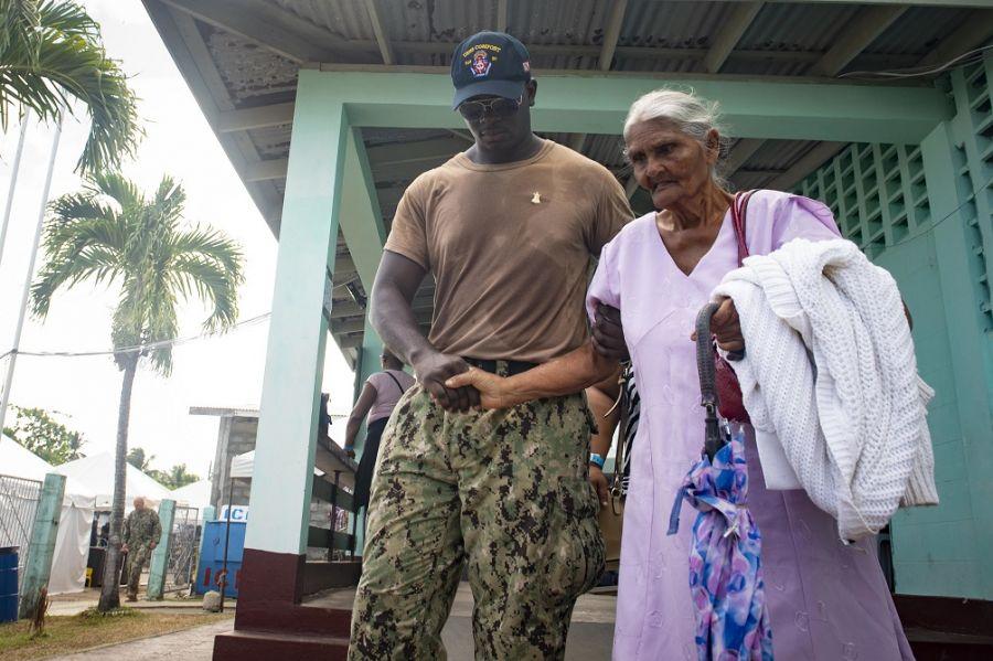 El Contramaestre de la Marina de los EE. UU. Miles Peterson acompaña a una mujer al puesto temporal de atención médica en Cedros, Trinidad. (Foto: Contramaestre Tercera Clase de la Marina de los EE. UU. Brendan Fitzgerald)