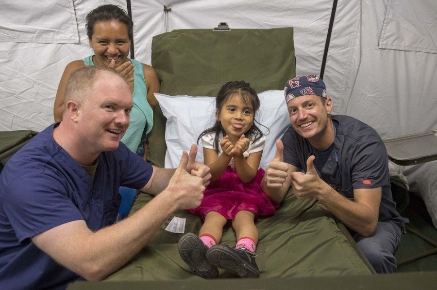 U.S. Navy Lieutenant Commander Conor Garry and Lieutenant Commander Jason Souza give a thumbs up with a Guatemalan girl during her post-surgery appointment at the expeditionary medical unit set up at the Guatemalan Navy’s Naval Caribbean Command in Puerto Barrios, Guatemala. (Photo: U.S. Navy Mass Communication Specialist Second Class Brianna K. Green)