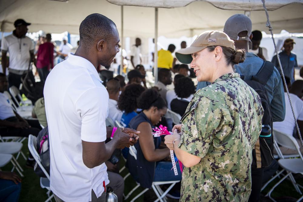 La Capitán de Corbeta de la Marina de los EE. UU. Anna Achlenker, especialista en enfermería clínica, asignada al buque hospital USNS Comfort (T-AH 20), reparte pulseras de identificación como traductor, en el sitio médico en Jeremie, Haití, durante Promesa Continua 2022, el 12 de diciembre de 2022. (Foto: Contramaestre Primera Clase de la Marina de los EE. UU. Benjamin Lewis)