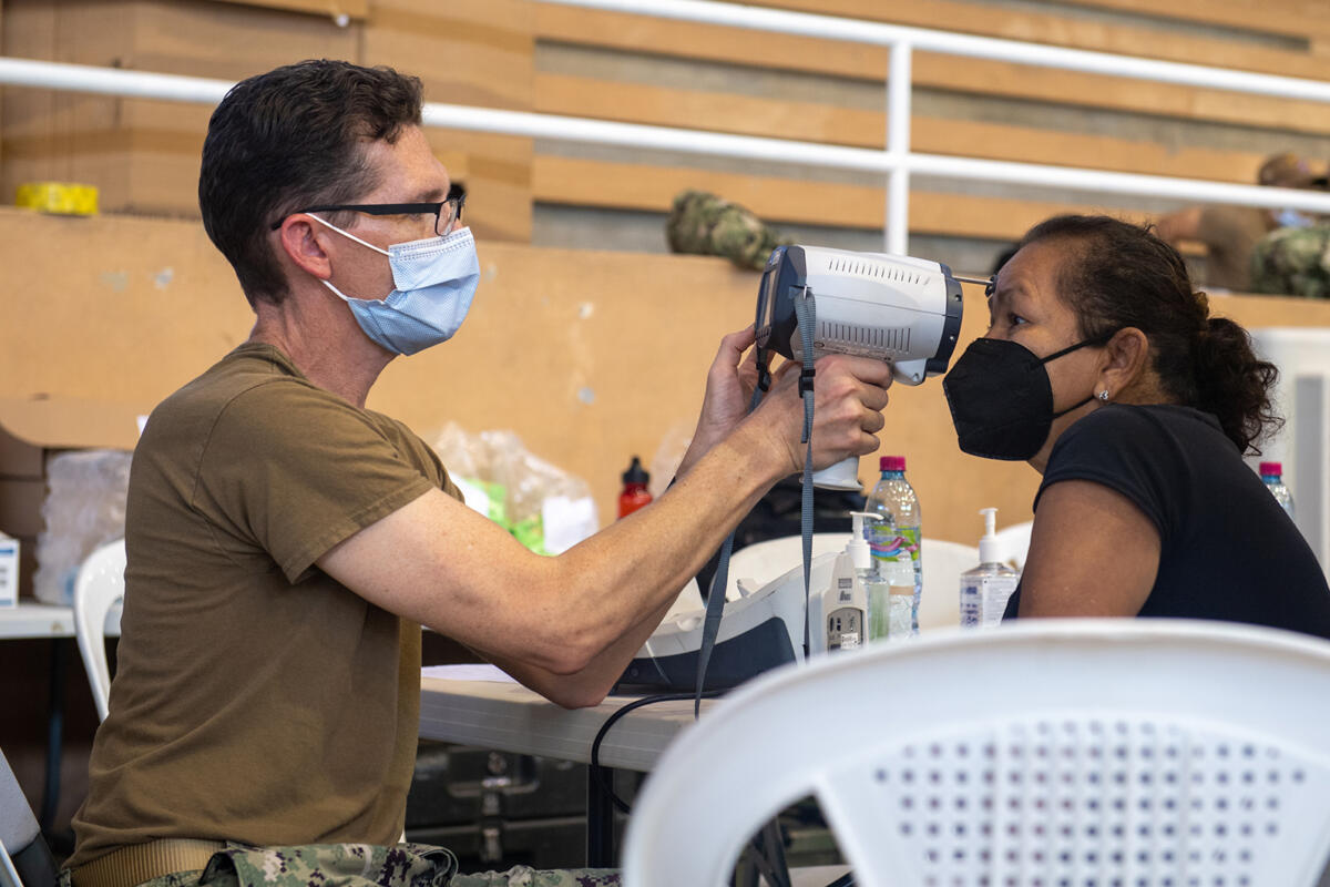 U.S. Navy Commander Joshua Keil, attached to the hospital ship USNS Comfort (T-AH 20), checks the eyes of a patient at the Continuing Promise medical site, October 28, 2022. (Photo: U.S. Navy Mass Communication Specialist Seaman Deven Fernandez) 