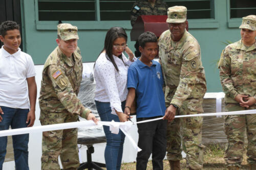 Una maestra y un estudiante hondureños; un funcionario de la Embajada de los EE. UU. en Tegucigalpa; un miembro del Comando Sur de los EE. UU. (SOUTHCOM); y un miembro del 410.º Batallón de Asuntos Civiles, cortan una cinta durante una ceremonia conmemorativa de una donación de equipo escolar en La Venta, Honduras, el 11 de abril de 2024. SOUTHCOM y el 410.º Batallón de Asuntos Civiles facilitaron e integraron a Consultores de Ayuda Mundial para donar nuevos pupitres, sillas y equipamiento a la escuela, como parte de la primera fase del ejercicio CENTAM Guardián 24. (Foto: Erica Bechard/Relaciones Públicas del Comando Sur de los EE. UU.)