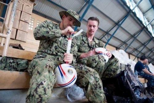 U.S. Navy Lt. j.g. Jack Dembowski (left) and Lt. j.g. Nick Moser, both attached to Destroyer Squadron 40, prepare soccer balls for distribution to patients at the CP-17 medical site in Puerto Barrios, Guatemala. (Photo: Mass Communication Specialist 2nd Class Shamira Purifoy/U.S. Navy)