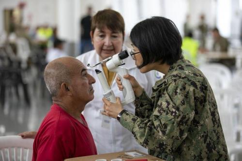 La Capitán de Corbeta de la Marina de los EE. UU.  Sandra Su, optometrista de Chicago, Illinois, realiza un examen de vista. (Foto: Especialista del Ejército de los EE. UU. Jacob Gleich)