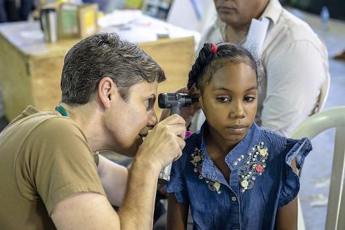 U.S. Navy Captain Jill Emerick, a doctor assigned to the USNS Comfort, examines a girl's ear at a temporary medical treatment site in Santo Domingo, Dominican Republic. (Photo: U.S. Navy Mass Communication Specialist Second Class Bobby J Siens) 