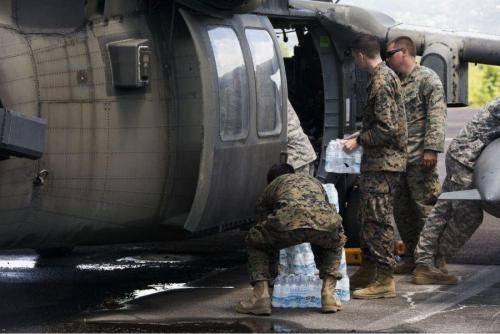 Membros do serviço dos EUA lotados na Força-Tarefa Conjunta-Leeward Islands carregam água num helicóptero UH-60 Black Hawk do Exército dos EUA no Aeroporto Internacional Aime Cesaire em Fort-de-France, Martinica, a ser levada para a ilha de Guadalupe.