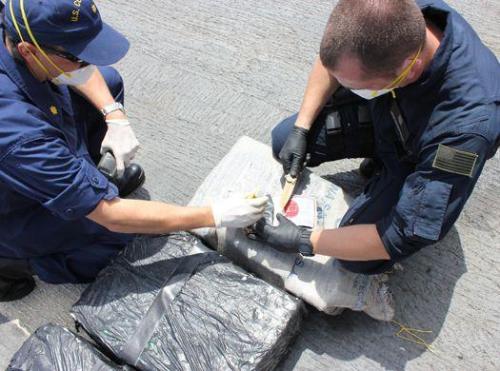 Tripulante do cúter Valiant, da Guarda Costeira dos EUA, examina um contrabando interceptado em 31 de março cujo teste deu positivo para cocaína. (Cortesia da Guarda Costeira dos EUA).