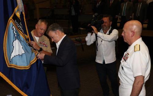 El presidente de Colombia Juan Manuel Santos coloca la medalla de la Orden de San Carlos en la bandera del SOUTHCOM, mientras lo observan el Almirante de la Marina de los EE. UU. Kurt W. Tidd, comandante del Comando Sur de los EE. UU., y el Sargento Mayor del Cuerpo de Infantería de Marina de los EE. UU. Bryan Zickefoose, sargento mayor de comando de SOUTHCOM. (Foto: José Ruiz, Relaciones Públicas del SOUTHCOM)