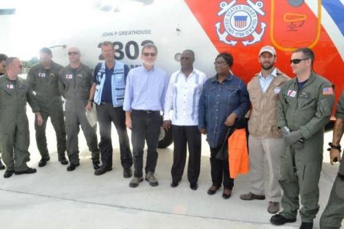 Peter Mulrean, embajador de los EE. UU. en Haití (centro) y Jocelerme Privert, presidente de Haití (a su izquierda), figuran entre los miembros de la comunidad de ayuda internacional junto con los tripulantes del HC-144 de la Guardia Costera de los EE. UU. (Foto: Guarda Costas de los EE. UU.) 