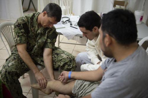 U.S. Navy Commander Edwin Landaker, a doctor assigned to USNS Comfort, examines a patient’s injury at a temporary medical treatment site. (Photo: U.S. Navy Mass Communication Specialist Second Class Julio Martinez Martinez)